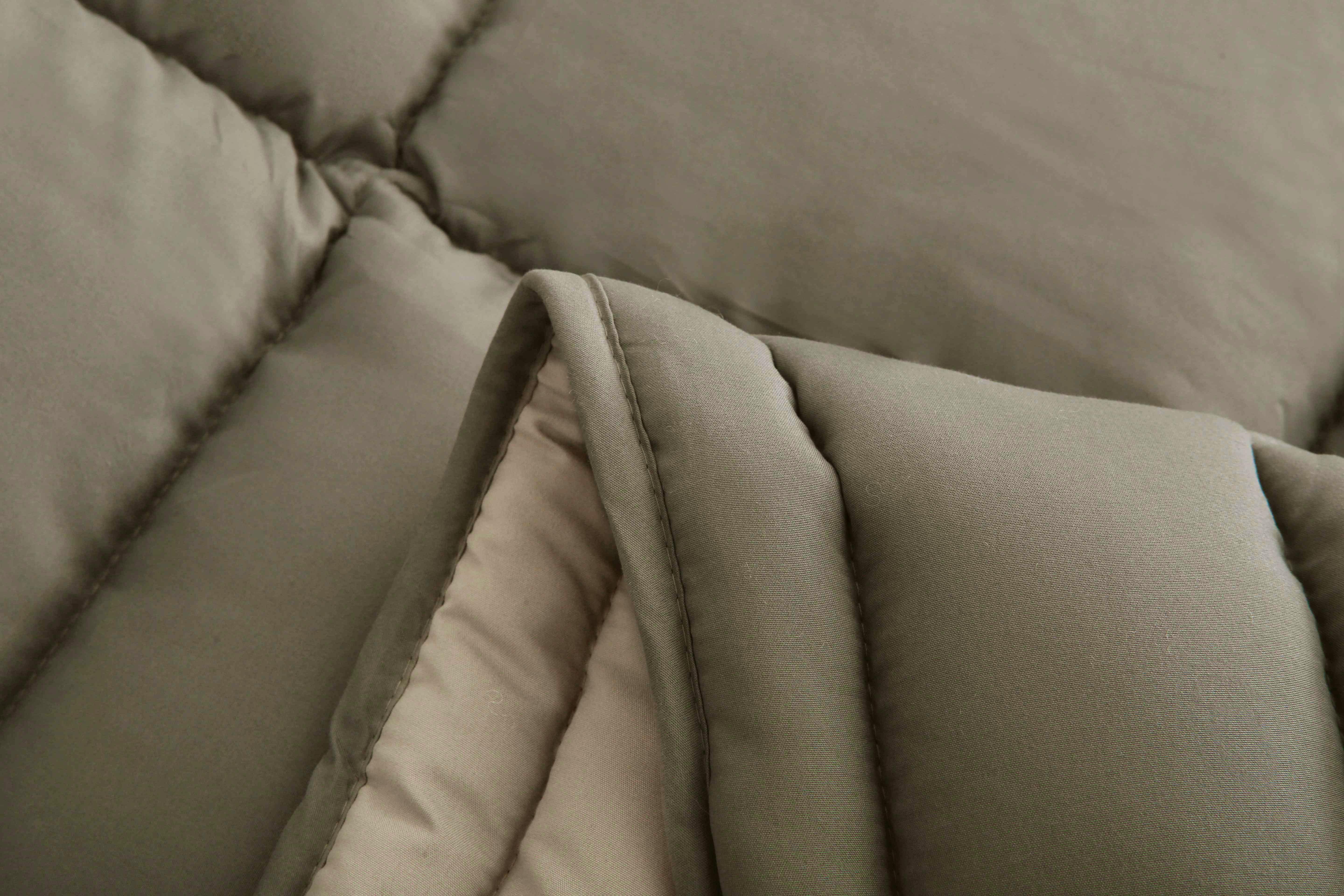 Close-up van de zachte microvezelstof van het taupe 4-seizoenen dekbed van Zorgmatras