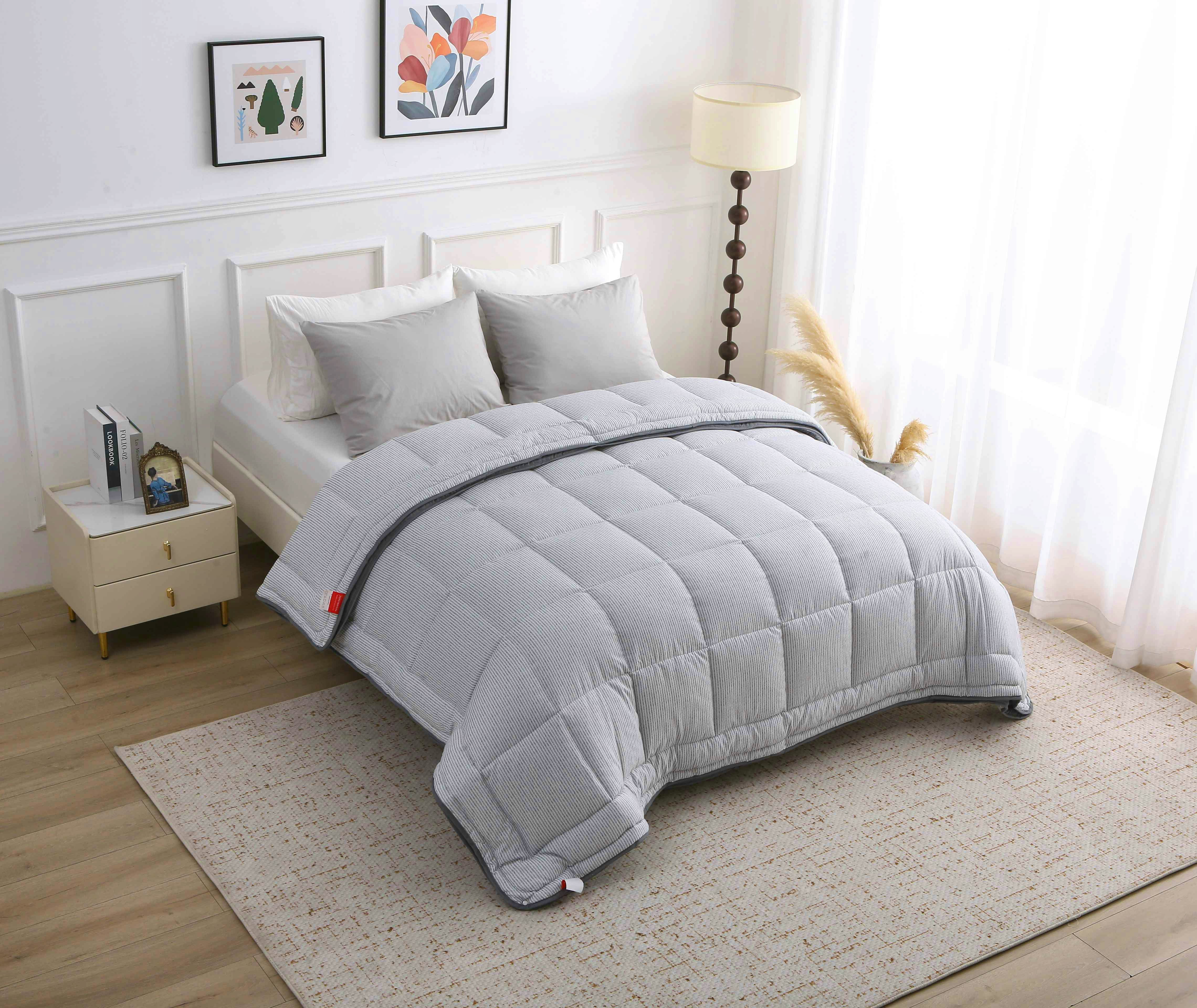 Overzicht van een stijlvol grijs gestreept 4-seizoenen dekbed zonder overtrek op een opgemaakt bed in een lichte slaapkamer
