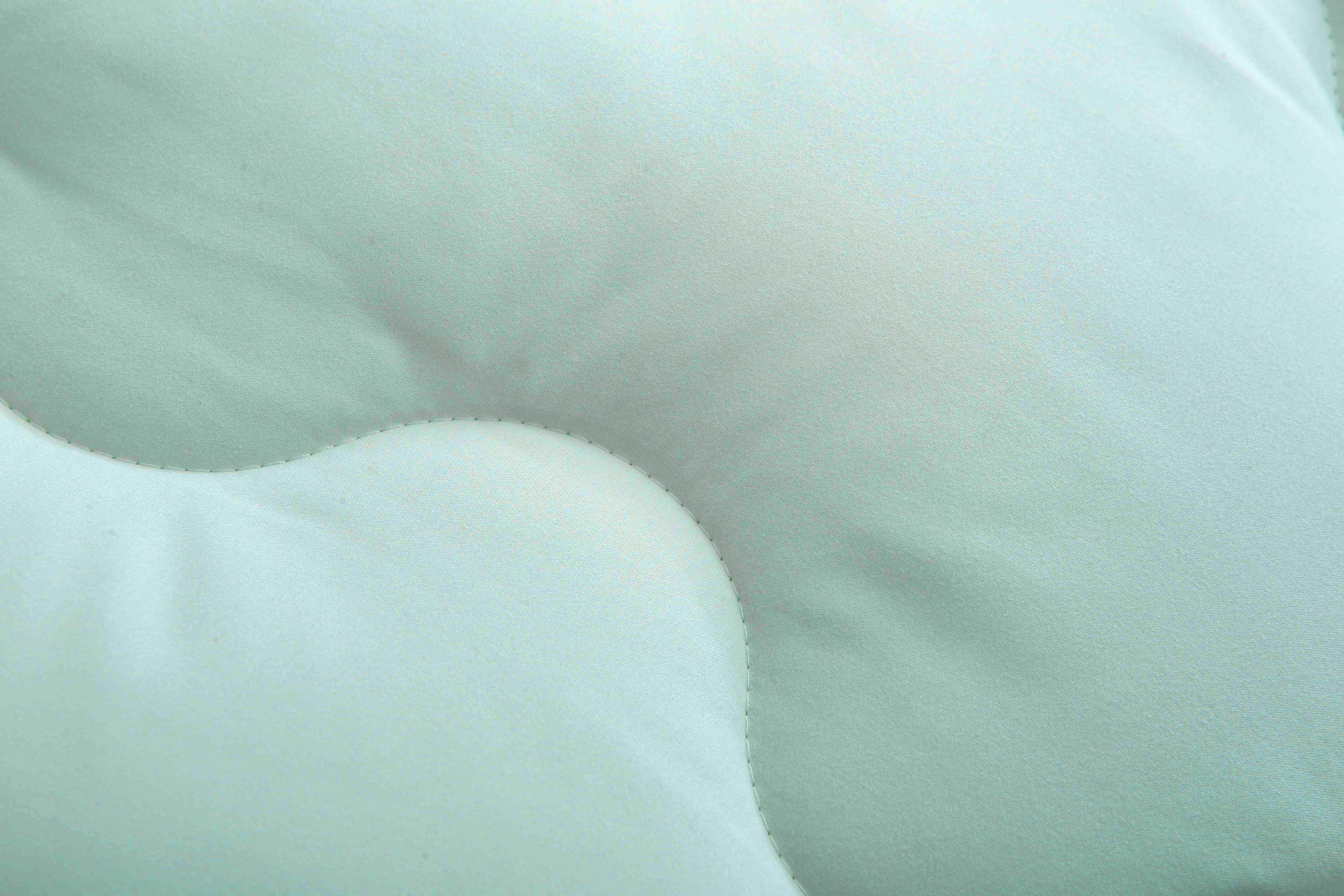 Detail van het stiksel van een lichtgroen dekbed zonder overtrek met ademende polyester vulling