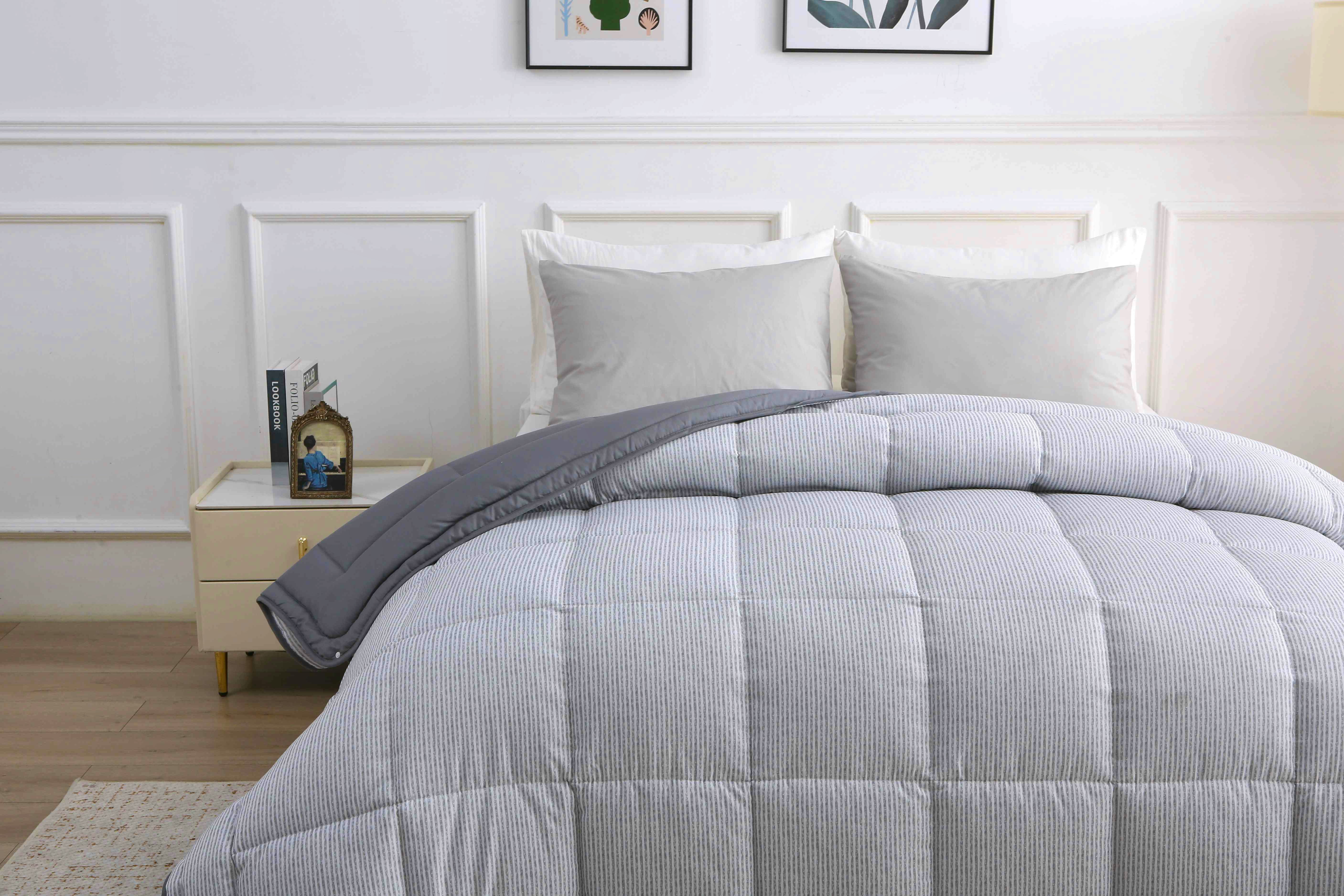Zijaanzicht van een opgemaakt bed met 4-seizoenen dekbed met grijs gestreepte vaste hoes