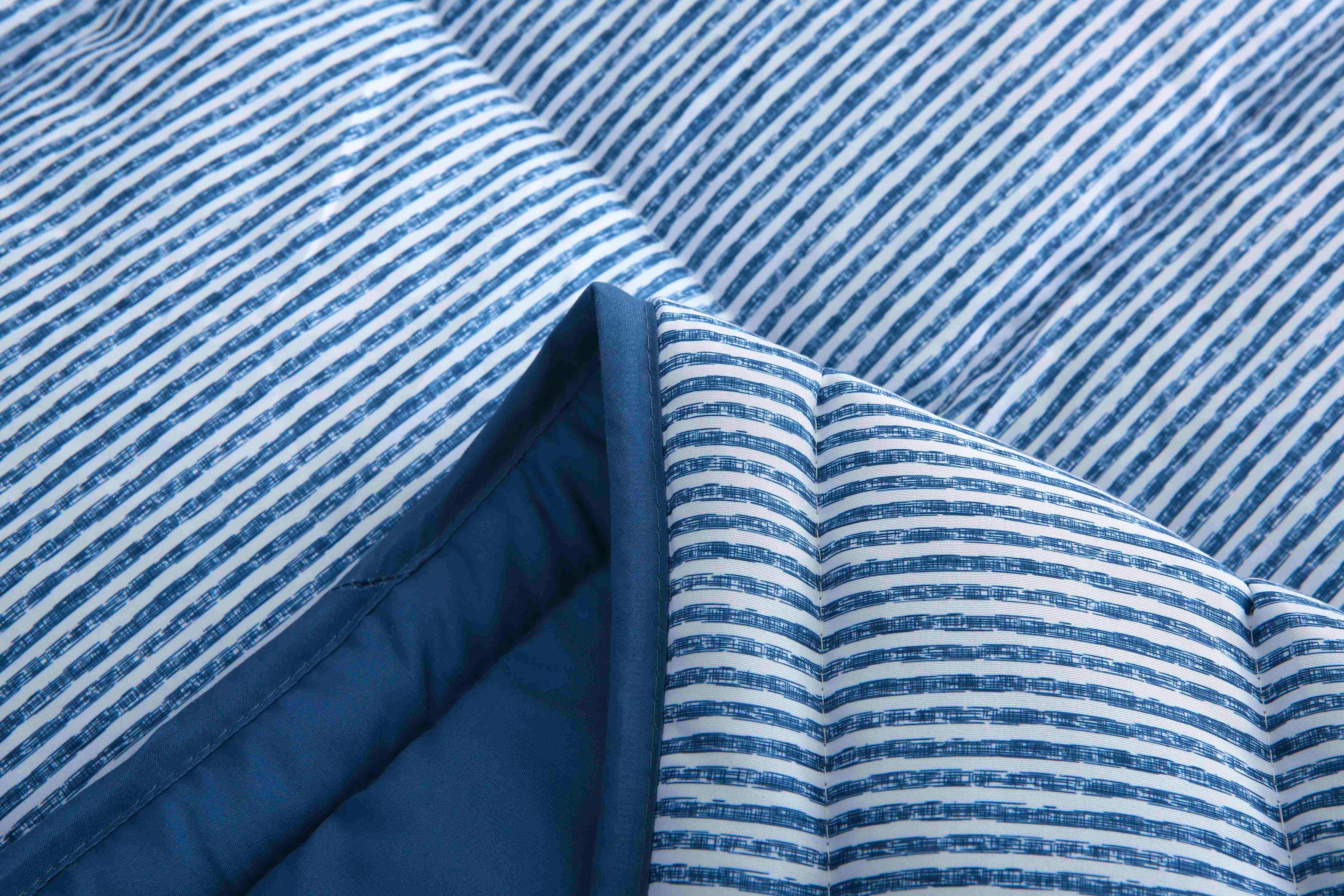 Close up van 4-seizoenen dekbed blauw gestreept, met zicht op effen gekleurde binnenkant 