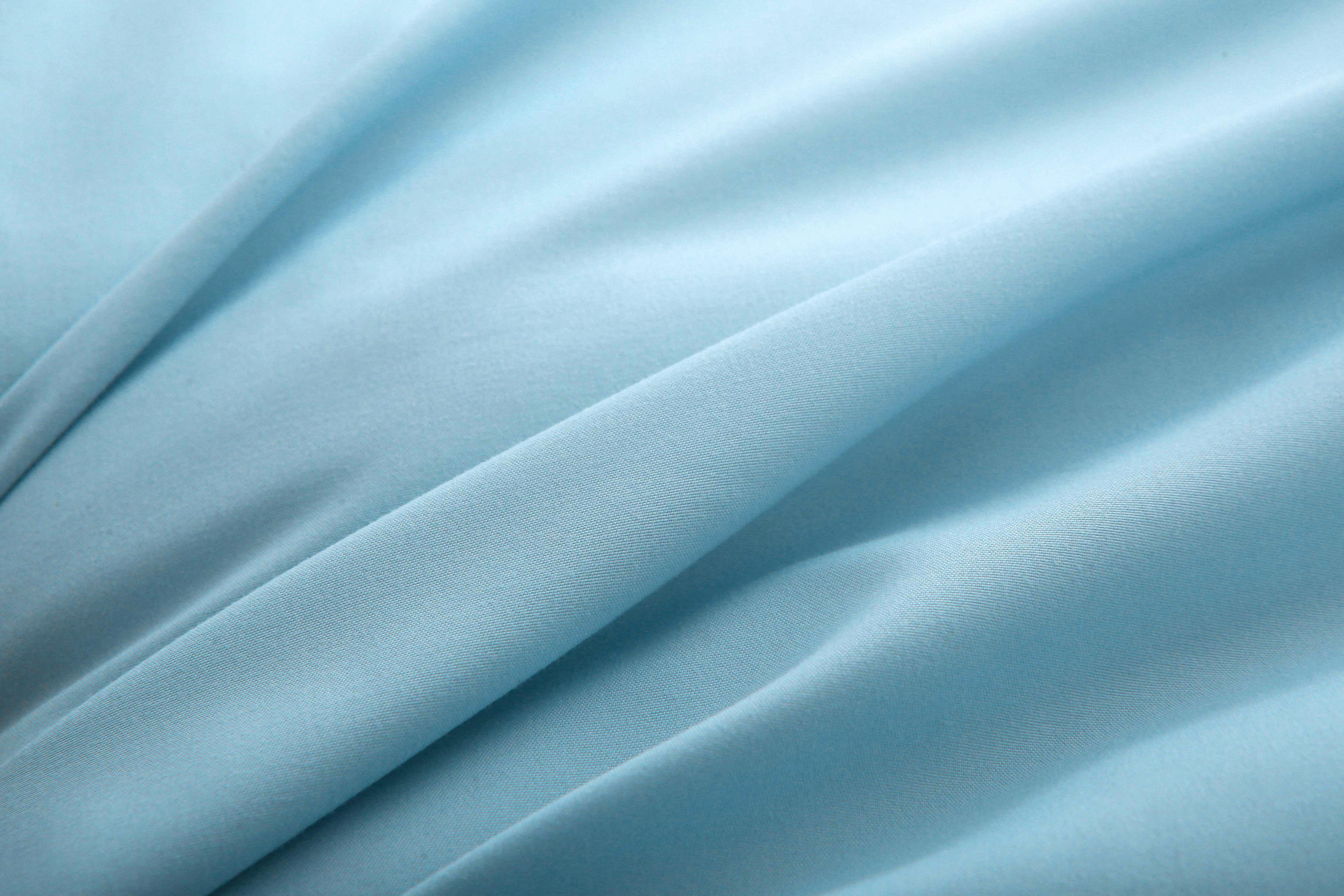 Close-up van zachte blauwe koelzijde van hoesloos zomerdekbed, gladde stofstructuur