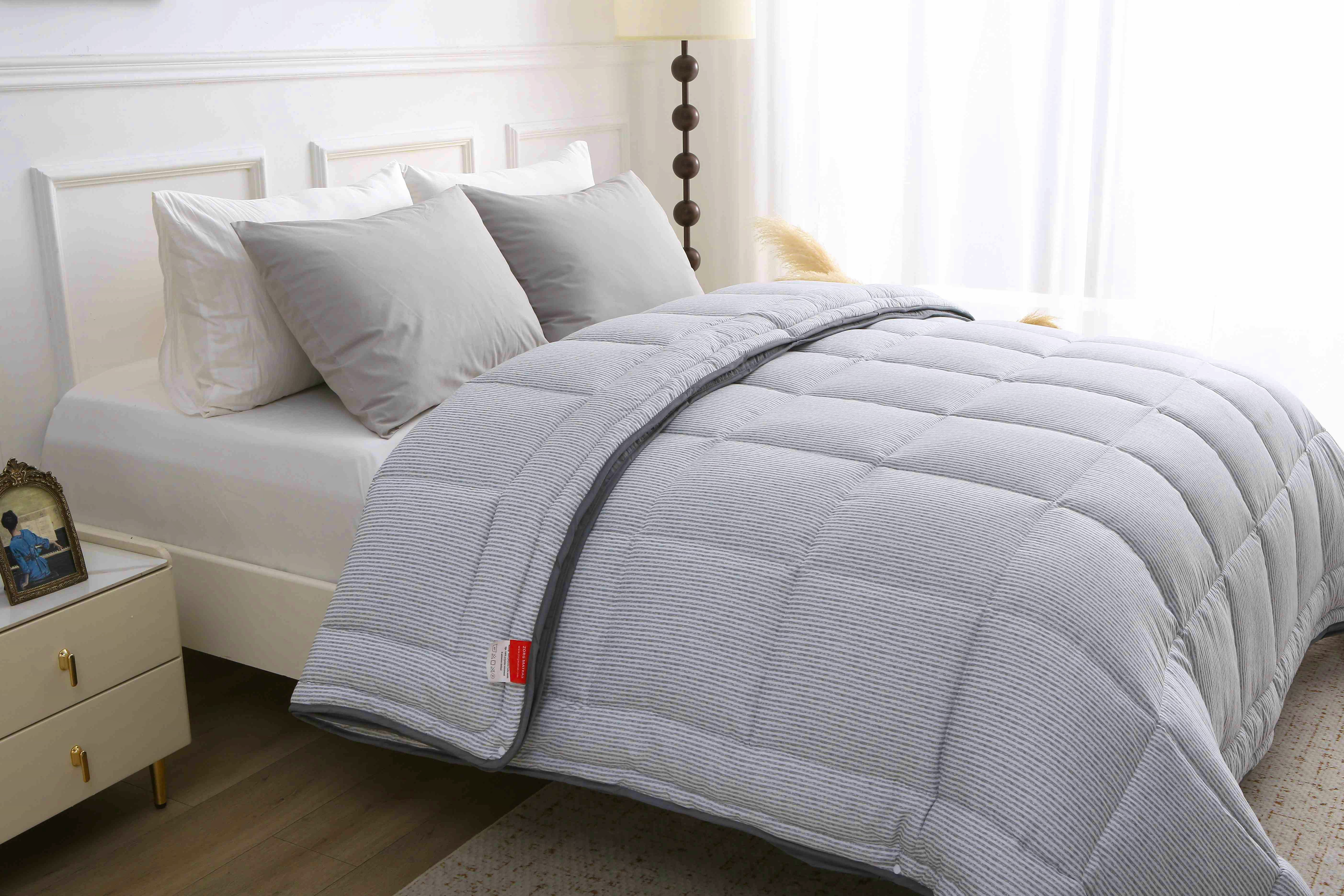 Detailopname van het grijs gestreepte dekbed zonder overtrek met vaste doorgestikte hoes